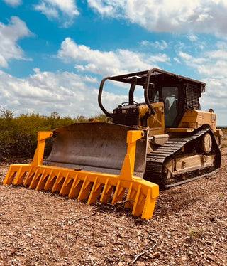 Yellow bulldozer on a dirt field with a blue sky and clouds in the background