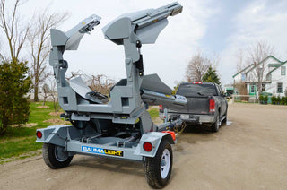 Gray tree pruner attached to a pickup truck on a driveway